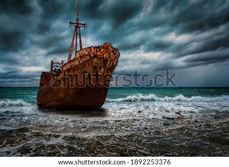 A stranded shipwreck at surf with rough sea and stormy sky