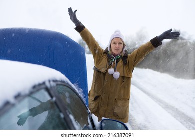 Stranded Woman Flagging Down Car In Snow