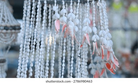 Strands of small white and pink shells hang together as a handmade wind chime.