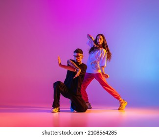 Strange Body Movements. Two Young People, Guy And Girl Dancing Contemporary Dance Over Pink Background In Neon Light. Modern Dance Aesthetics Concept