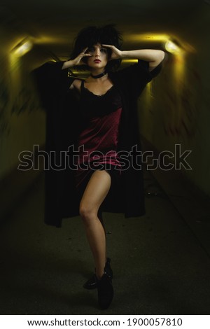 Strange and freaky woman with a disheveled hair in the dark tunnel