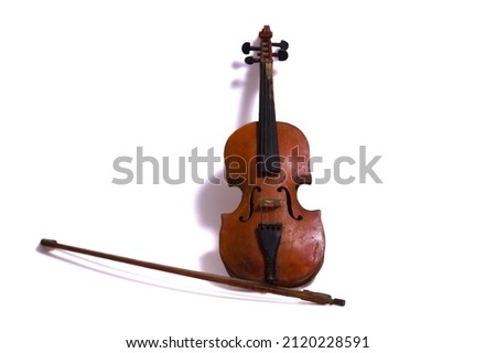 Strange homemade old roughly made brown violin with a fiddlestick on a white background