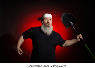 A Strange Man With A Beard With A Bandage On His Head Runs With A Shovel On A Red Background