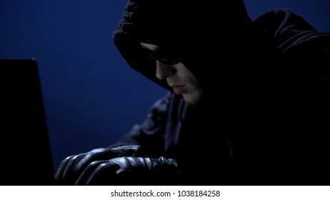 Strange man in black clothes, sunglasses and gloves stealing data from laptop - Shutterstock ID 1038184258
