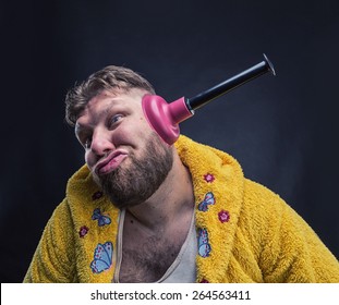 Strange man in a terry bathrobe with a plunger in his ear 