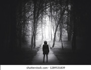 Strange Portal to the other world. Girl goes on the scary road in the paranormal world. Dark mysterious park in a fog. Scary forest lit by moon. Black and white arthouse