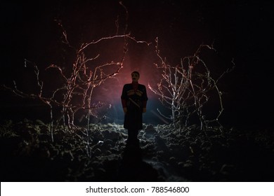 Strange Silhouette In A Dark Spooky Forest At Night, Mystical Landscape Surreal Lights With Creepy Man