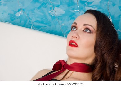 Strangled beautiful woman in black dress lies on the couch. Simulation of the crime scene.