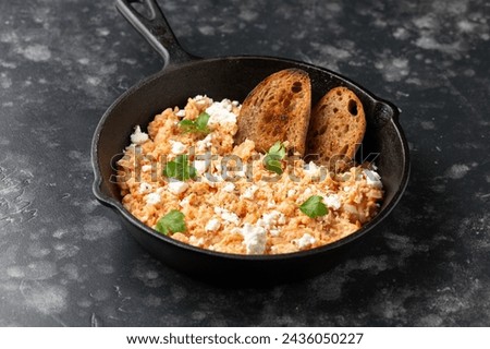 Strapatsada, eggs scrambled with bread, tomatoes and feta cheese in iron cast pan. Greek breakfast