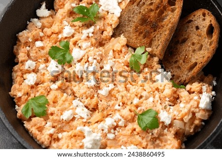 Strapatsada, eggs scrambled with bread, tomatoes and feta cheese in iron cast pan. Greek breakfast