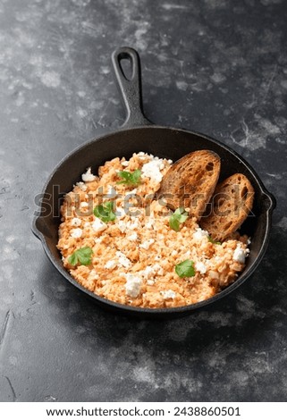 Strapatsada, eggs scrambled with bread, tomatoes and feta cheese in iron cast pan. Greek breakfast
