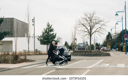 STRASBOURG, FRANCE - APR 2, 2018: Volkswagen Black Car Lets Female Couple Crossing Street Pushing Stroller