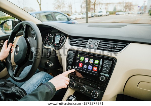 Strasbourg, France - Dec 13, 2016: Woman\
inside luxury car interior with Apple CarPlay system on the large\
digital dashboard with all apps on the digital\
screen