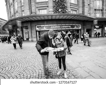 Strasbourg, France - Dec 29, 2018: Tourists, Father And Daughter Looking At The City Map In Front Of The Galeries Lafayette Shopping Mall Center In Central Strasbourg, Black And White