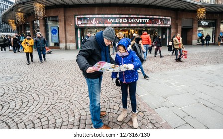 Strasbourg, France - Dec 29, 2018: Tourists, Father And Daughter Looking At The City Map In Front Of The Galeries Lafayette Shopping Mall Center In Central Strasbourg,