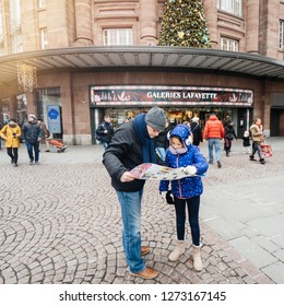 Strasbourg, France - Dec 29, 2018: Tourists, Father And Daughter Looking At The City Map In Front Of The Galeries Lafayette Shopping Mall Center In Central Strasbourg, Square Image