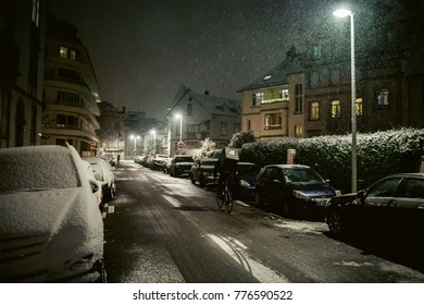 STRASBOURG, FRANCE - DEC 3 2017: Deliveroo Delivery Bike In French City Cycling Fast For Food Delivery On Time On A Cold Winter Snowy Night In Residential Neighborhood