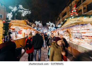 STRASBOURG, FRANCE - DEC 6, 2015: Adults, Childrens, Grandparents And Happy People Walking During Christmas Market Admiring Market Stall, Buying Food, Presents And Toys 