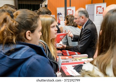 STRASBOURG, FRANCE - FEB 4, 2016: Children and teens of all ages attending annual Education Fair to choose career path and receive vocational counseling - professor explaining