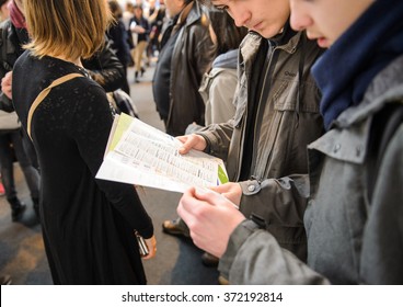 STRASBOURG, FRANCE - FEB 4, 2016: Children and teens of all ages attending annual Education Fair to choose career path and receive vocational counseling - bous reading flyer