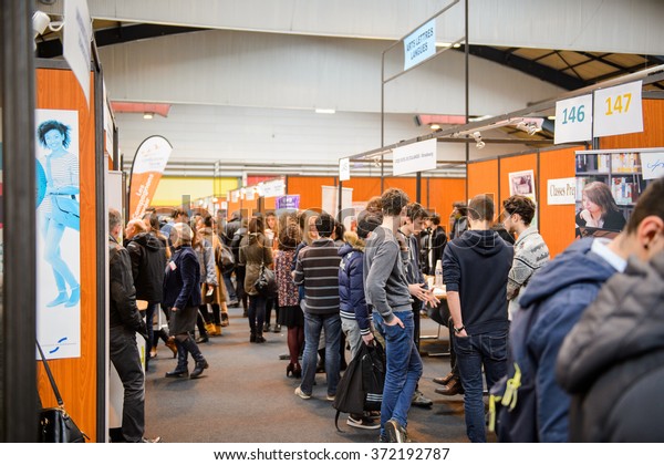 STRASBOURG, FRANCE -\
FEB 4, 2016: Children and teens of all ages attending annual\
Education Fair to choose career path and receive vocational\
counseling - rows of college\
stands