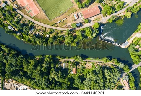 Strasbourg, France. Football field and garden plots. Riffle with a dam on the Ill River. Panorama on a summer day. Sunny weather. Aerial view