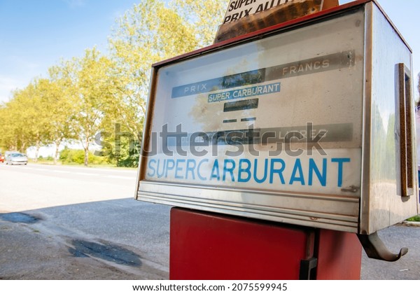 Strasbourg, France - Jul 2, 2013: Vintage old\
Themis gas meter with volume sign and old French francs counter per\
liter. Super Carburant - cars in\
background