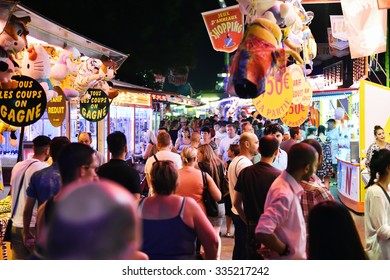 STRASBOURG, FRANCE - JULY 19, 2015: Crowd Of People Late Night In Amusement Park Admiring Diverse Offers