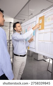 Strategy coaching session. Experienced confident mid adult male team leader mentor explain business planning ideas to younger coworker intern demonstrate process flow teach project coordination basics