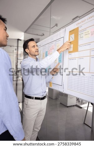Strategy coaching session. Experienced confident mid adult male team leader mentor explain business planning ideas to younger coworker intern demonstrate process flow teach project coordination basics