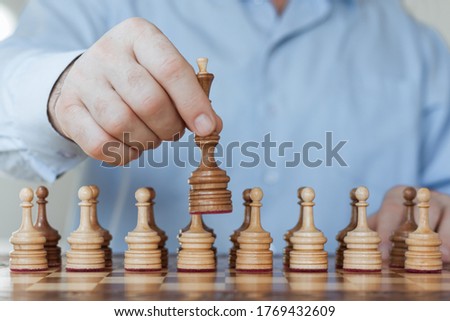 Strategy concept, hand of businessman moving wooden chess figure in play, management or leadership competition success background