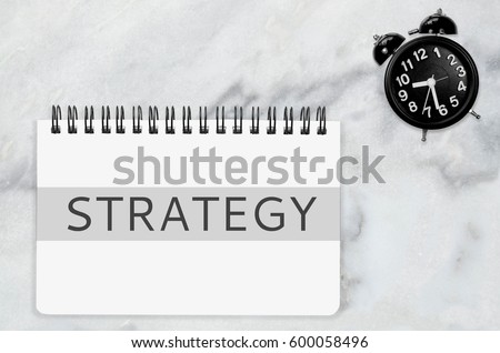 Strategy concept. white book write text strategy and black clock on white marble desk office tactic strategy generalship stratagem procedure process array procession technique business secret solution