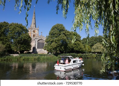 STRATFORD-UPON-AVON, WARWICKSHIRE, ENGLAND - AUGUST 27, 2017: Holy Trinity Church (Shakespeare's burial place) on the River Avon with tour boat