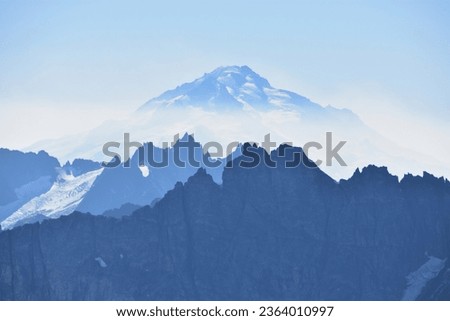 Stratovolcano Glacier Peak rises above wildfire smoke surrounding the nearby peaks of the North Cascades - Washington, Pacific Northwest, USA