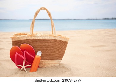 Straw bag, flip flops, starfish and sunscreen on beach, space for text - Powered by Shutterstock