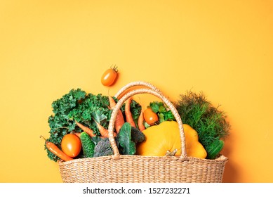 Strohkorb mit organischem Gemüse auf trendigem gelbem Hintergrund. Gesundes Essen, vegetarische Ernährung. Umweltfreundlich, ohne Abfälle, plastikfreies Konzept