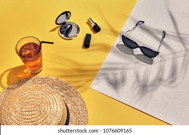 Straw Beach Woman's Hat And Sun Glasses, Top View Yellow And White Paper Background With Shadow From A Palm Leaf.