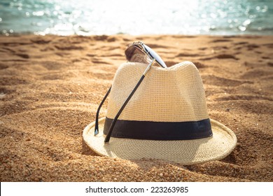straw fedora hat on sandy beach 