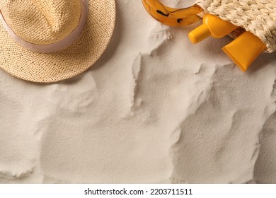 Straw Hat And Bag With Sunscreen On Sand, Flat Lay. Space For Text