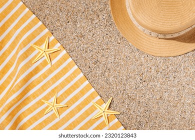 Straw hat and beach towel on the beach sand - Powered by Shutterstock