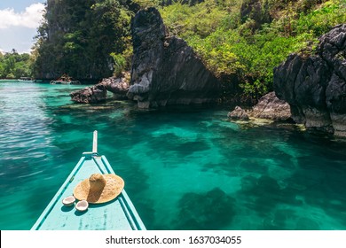 Straw hat and coconut on boat over clear sea water vith lagoon view. Travelling tour to lagoon in Asia: El Nido, Palawan, Philippines.