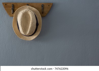 Straw Hat Hanging On Hook Against Wall