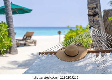 A straw hat lying on the hammock in the background of the landscape of the Maldives. Travel and tropical vacation concept. 