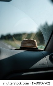 A straw hat put on a front window of a car during a road trip on a sunny day