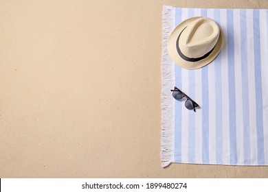 Straw Hat, Sunglasses, Blanket And Space For Text On Beach Sand, Top View. Summer Vacation