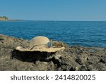 Straw hat with sunglasses on rocks on the seashore