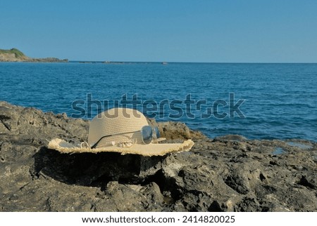 Straw hat with sunglasses on rocks on the seashore
