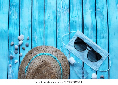 Straw Hat, Sunglasses, Pebbles, Medical Mask And Antiseptic On A Wooden Background. The Travel Ban Is Linked To The Covid-19 Coronavirus Epidemic. Tourist Crisis In The Summer Of 2020