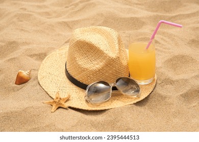 Straw hat, sunglasses and refreshing drink on sand. Beach accessories - Shutterstock ID 2395444513