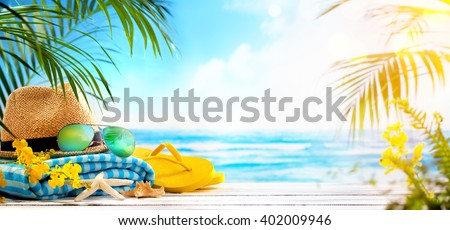 Straw hat, towel, sun glasses and flip flops on beach